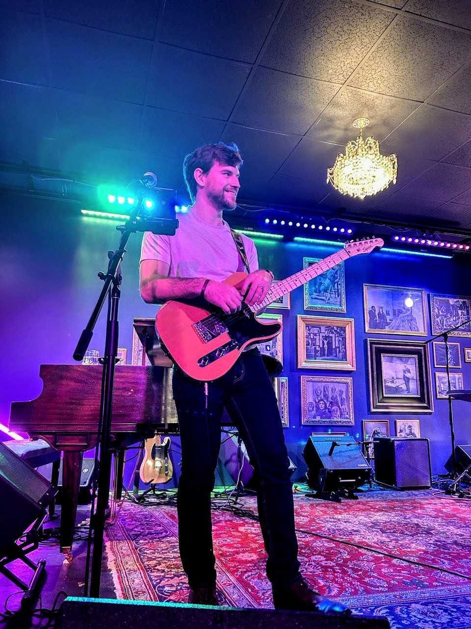 Thibault on stage playing a pink electric guitar